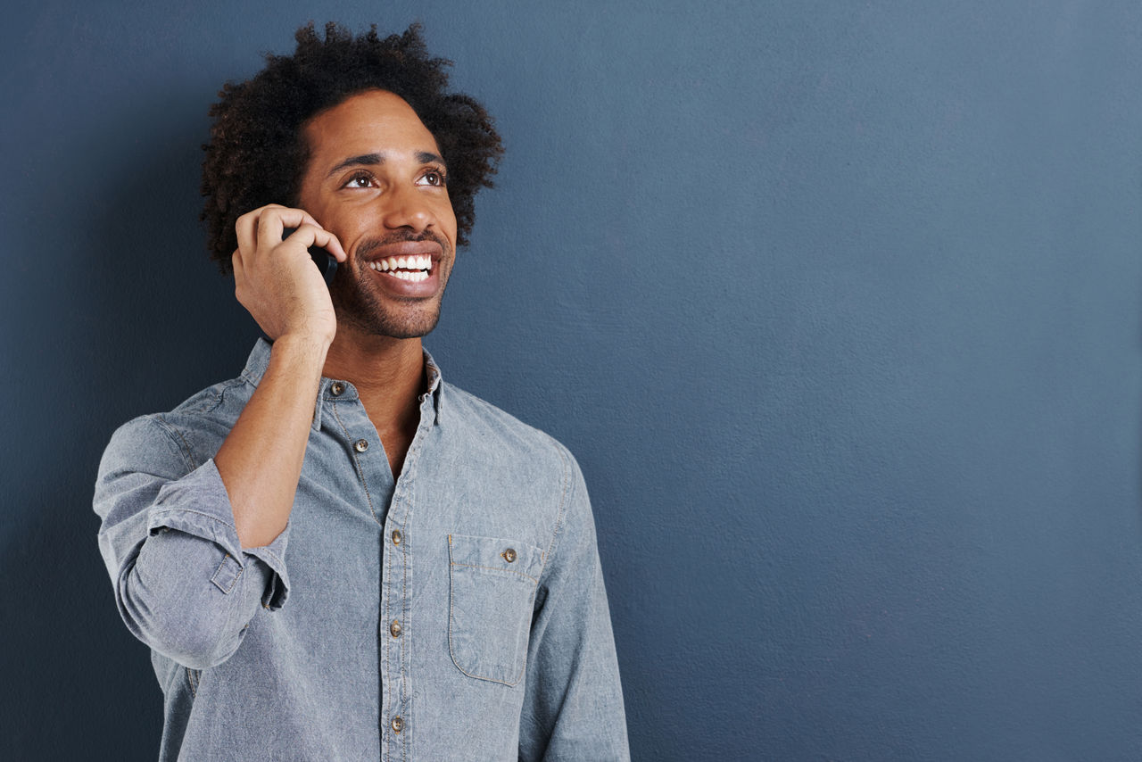 Shot of a happy young man talking on a cellphone on a gray background