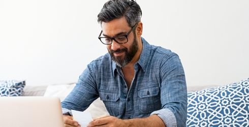 man wearing glasses sitting down in front of laptop